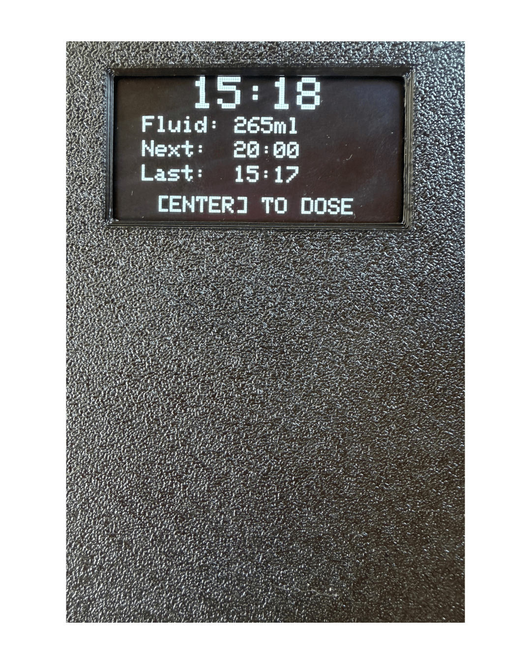 Close-up of a dark textured electronic device with a small black display screen showing white text and status information.